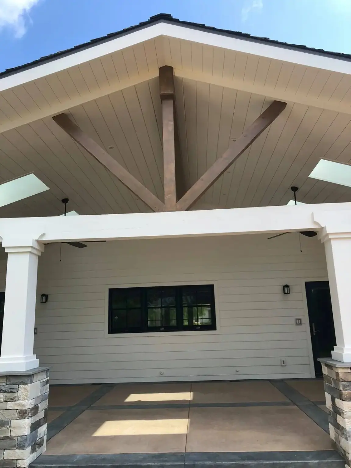 Completed covered patio with a vaulted ceiling, exposed beams, and stone column bases