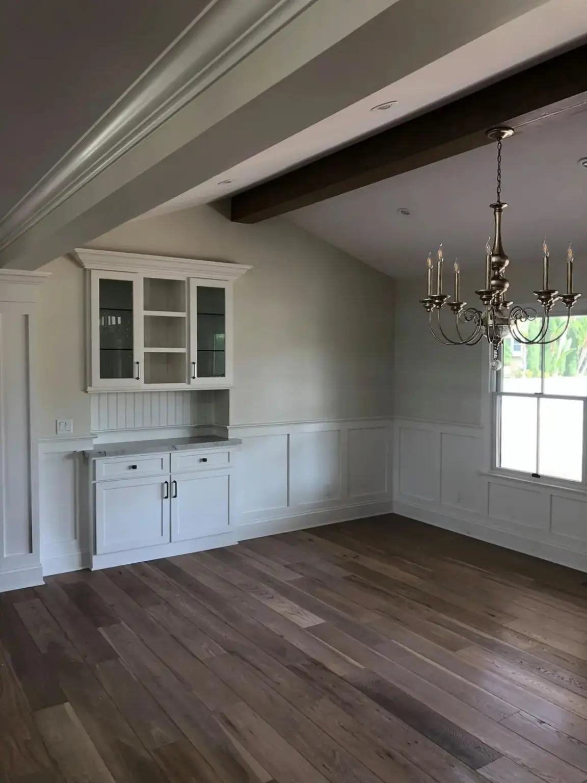 Completed dining room with custom built-in cabinetry, wainscoting, and wood flooring