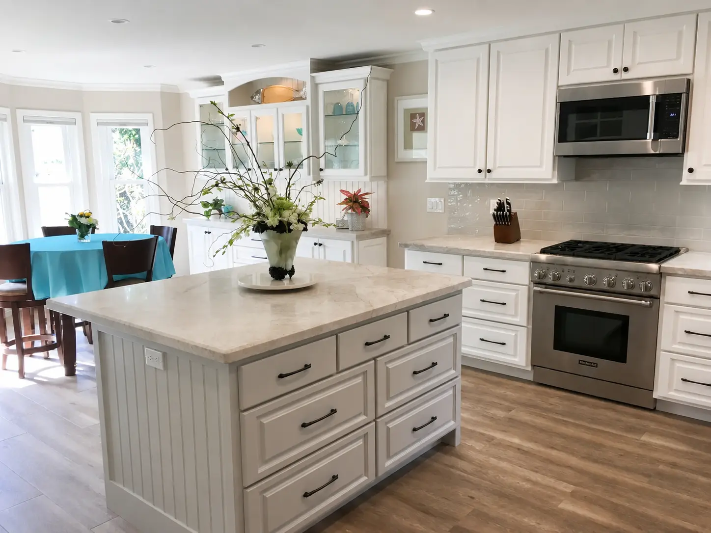 Completed bright kitchen with custom white cabinetry, stone island, professional range, and black hardware