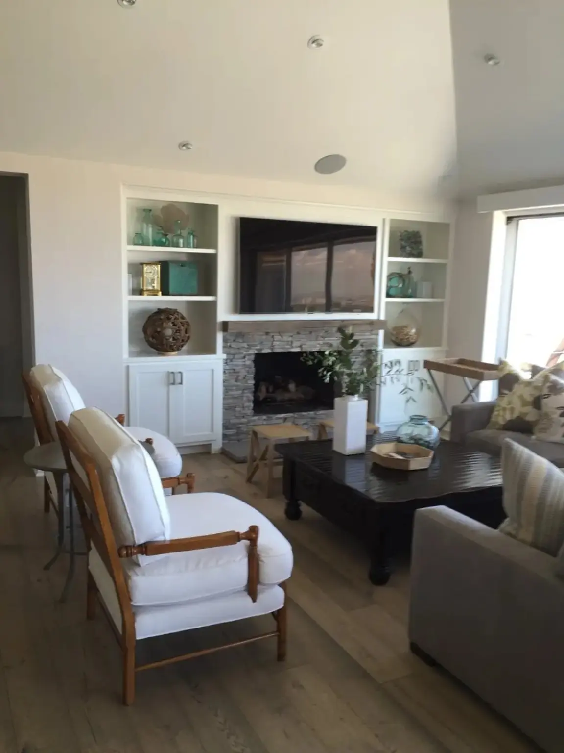 Completed living room renovation with stone fireplace and white built-in cabinetry