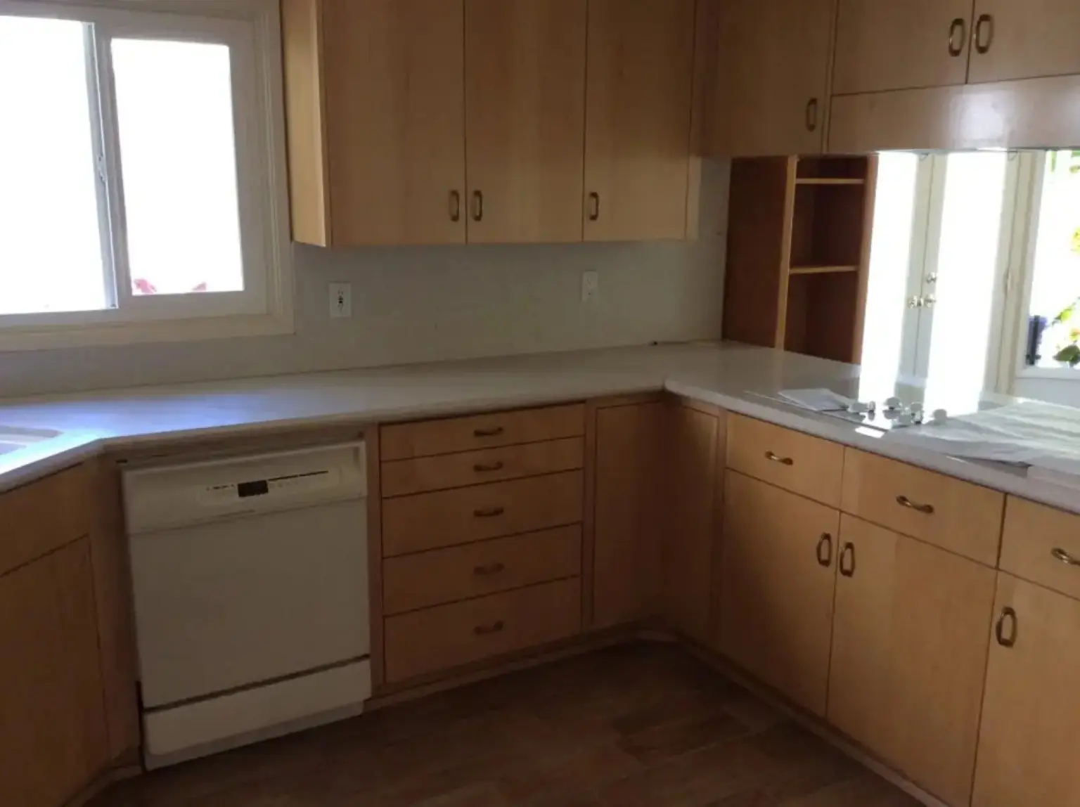 Kitchen before JBI renovation with natural wood cabinetry and older appliances