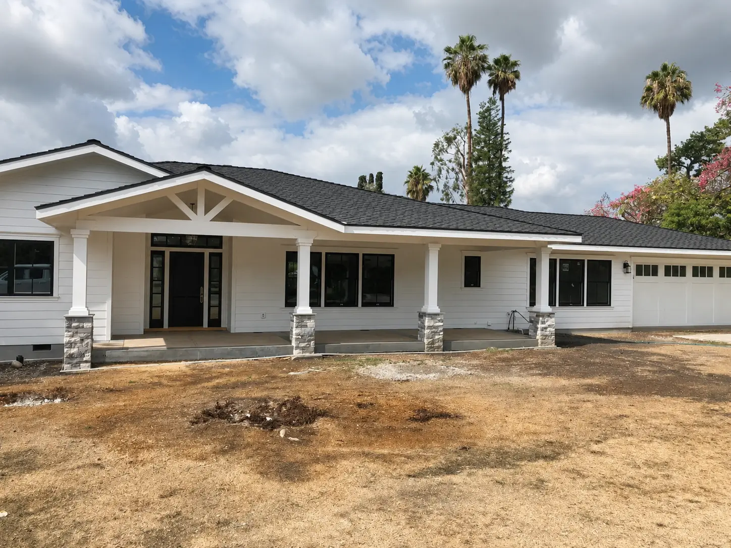 Completed JBI residential project with a long covered front porch, stone columns, and black-framed windows